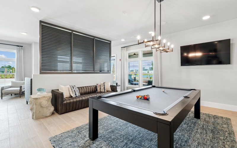 a room with a couch, chairs, & a pool table
