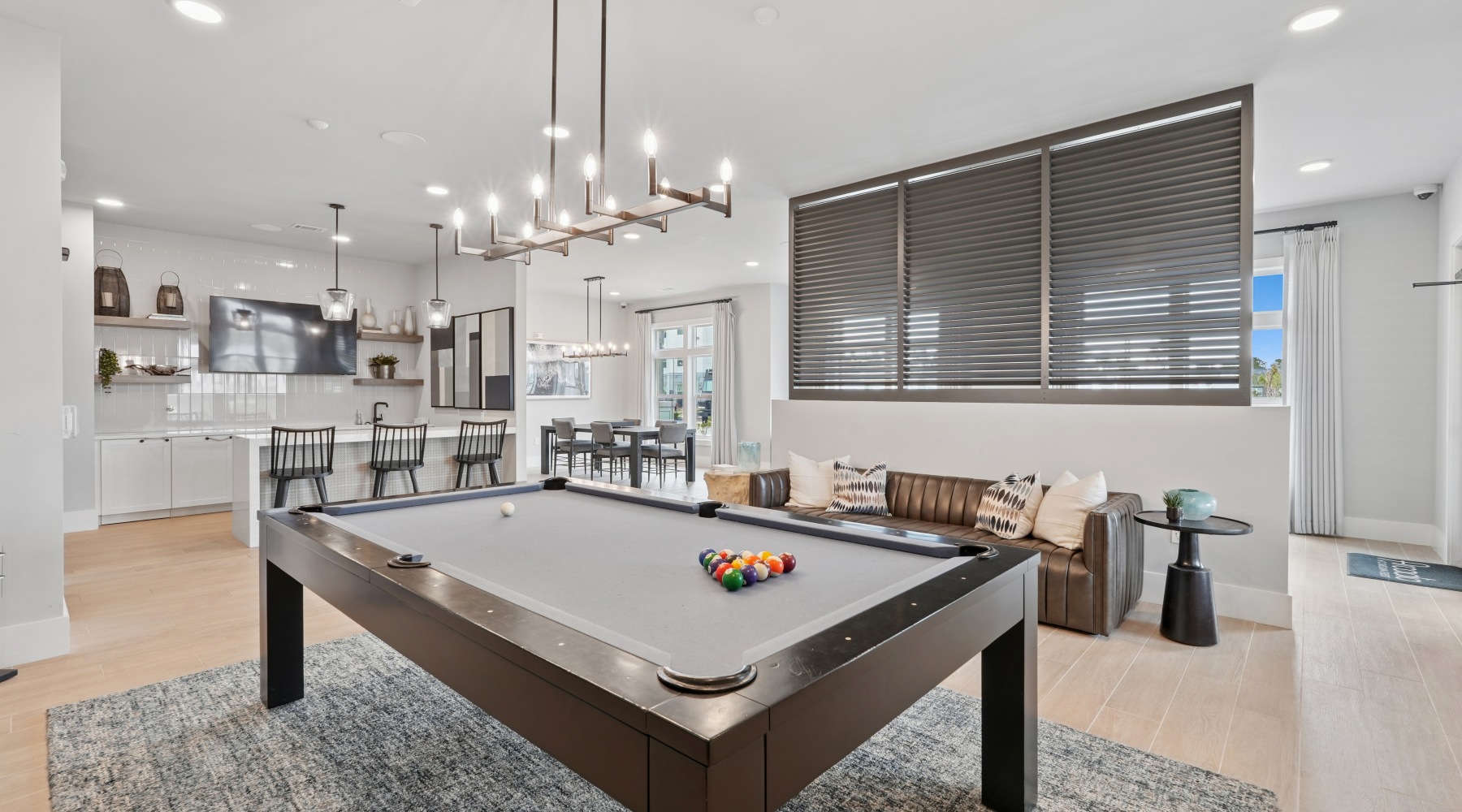 a room with a pool table and a kitchen behind it